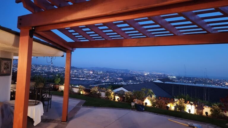 Custom wooden patio pergola overlooking cityscape at dusk, featuring outdoor living space.