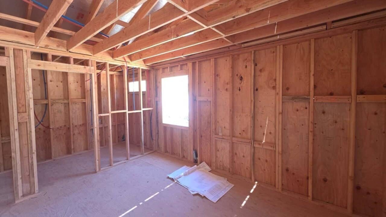 Interior view of a room addition framing, showing wooden framing, exposed walls, and a window with natural light.