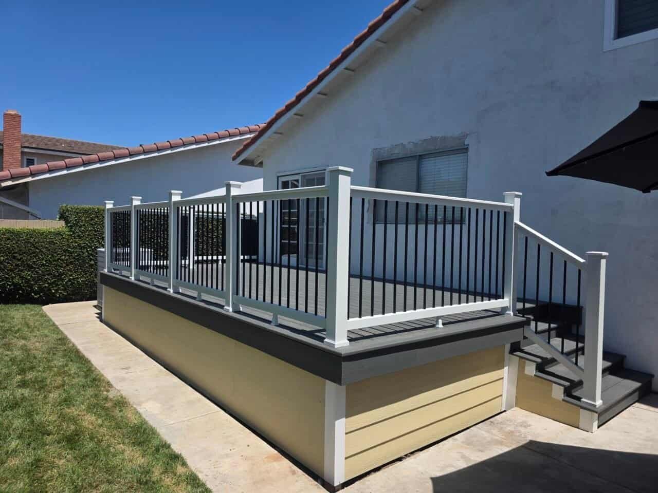 Elevated gray composite deck with white railings and black balusters installed on a residential home in Irvine, California